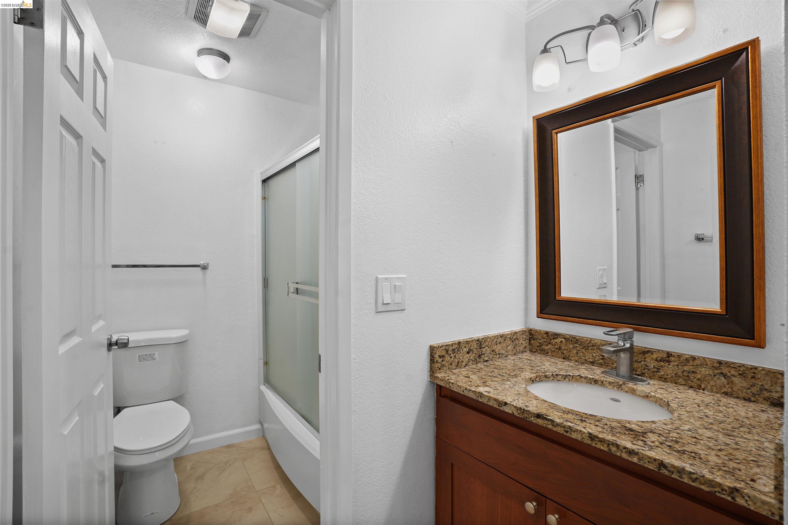 1505 Kirker Pass Road, Unit 214 Concord, CA 94521 - Photo 35 of 55 Bathroom featuring a wood-finish vanity with a granite-style countertop, undermount sink, and chrome faucet