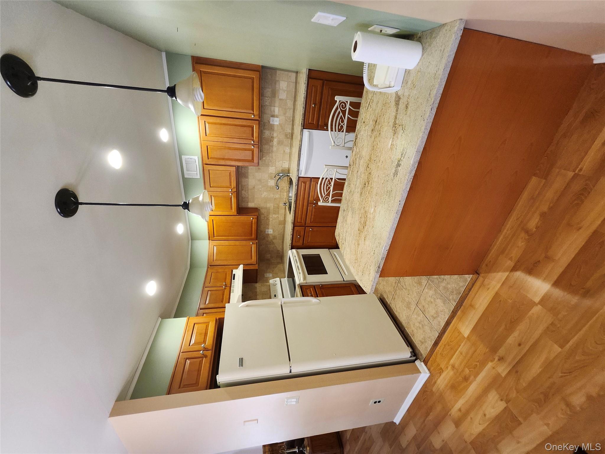 108 Village Road, Unit B Yorktown Heights, NY 10598 - Photo 41 of 42 a kitchen with kitchen island a stove a sink a refrigerator a counter top space and cabinets