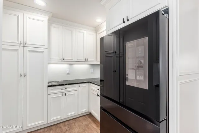a kitchen with granite countertop white cabinets and refrigerator