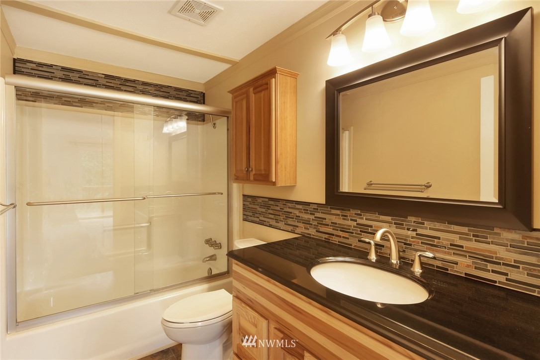 4030 Bay Road Ferndale, WA 98248 - Photo 19 of 36 a bathroom with a granite countertop sink toilet a mirror and shower