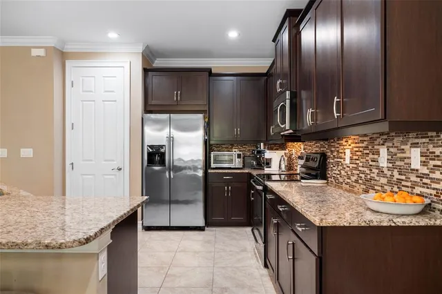 a kitchen with granite countertop stainless steel appliances a sink stove and refrigerator