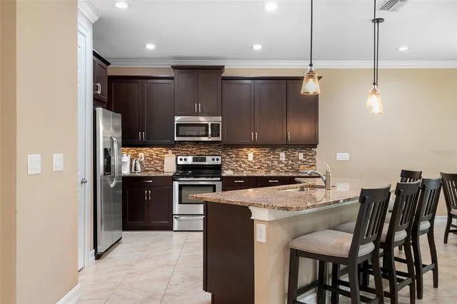 a kitchen with a refrigerator a stove a microwave oven a sink with island and chairs