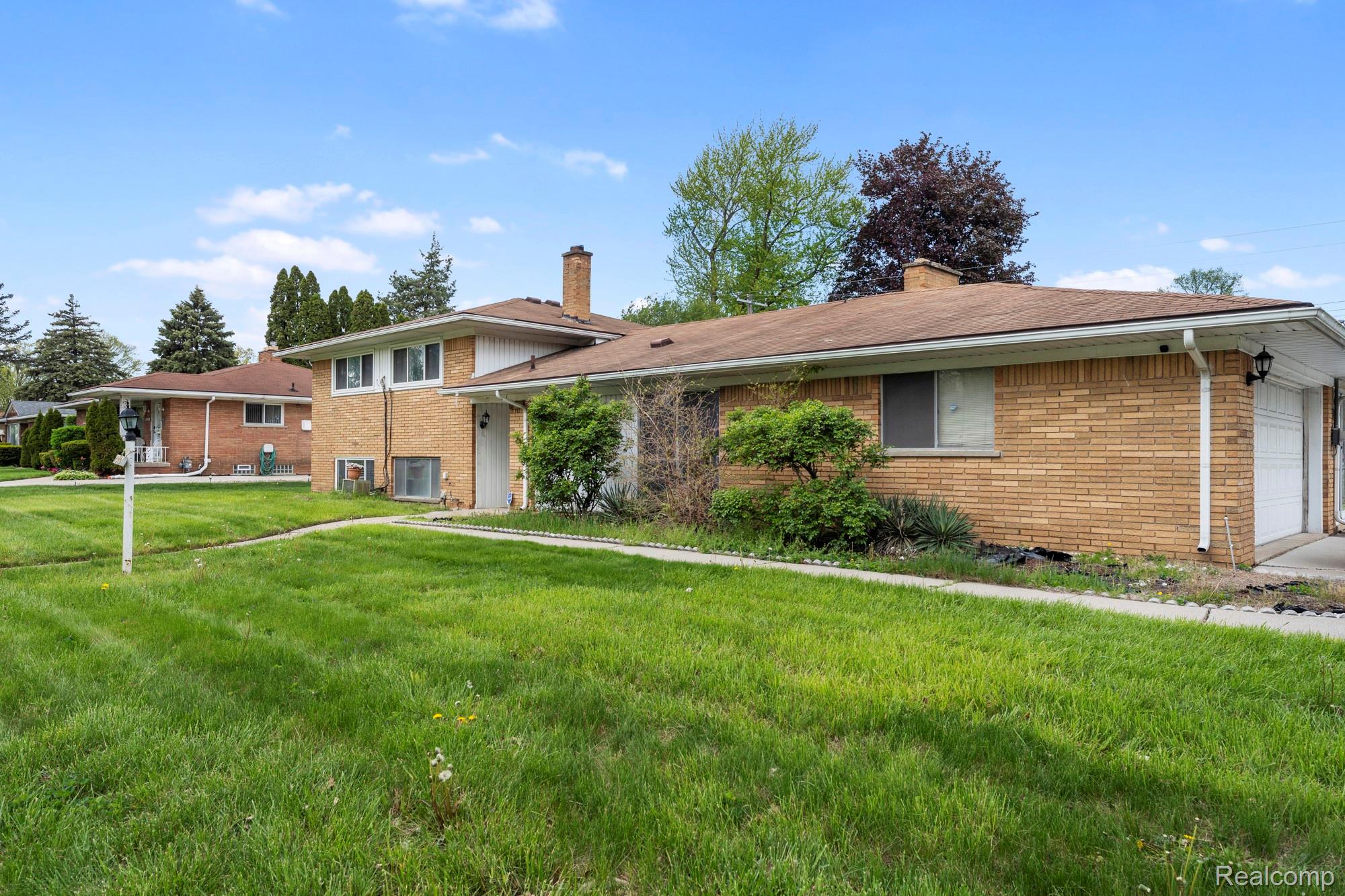 23410 Joy Road Redford, MI 48239 - Photo 1 of 25 Tri-level home with a chimney, brick siding, and an attached garage