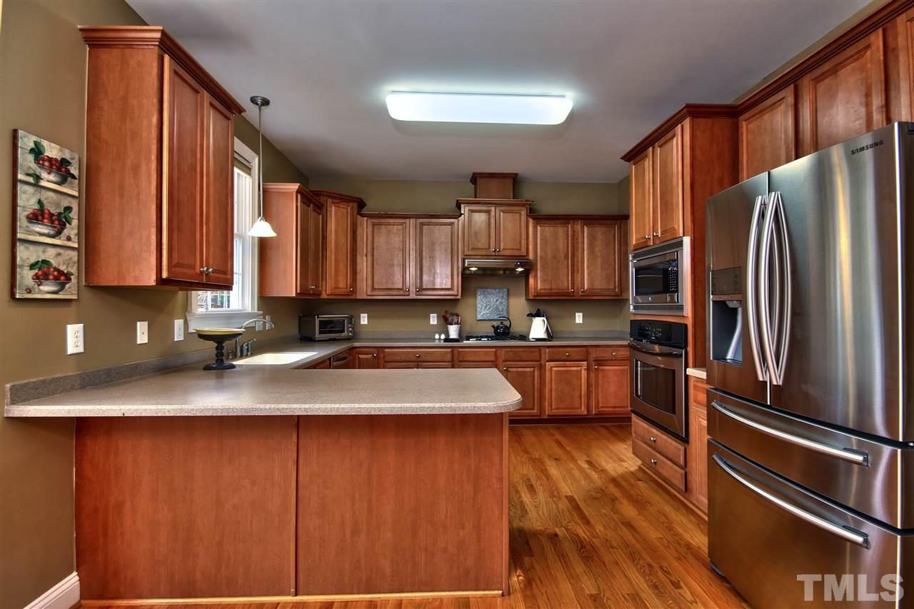 1100 Silas Ridge Court Raleigh, NC 27609 - Photo 8 of 24 a kitchen with stainless steel appliances granite countertop a refrigerator a sink dishwasher a stove top oven a large island with wooden floor and cabinets
