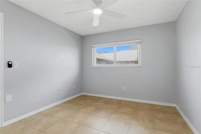 an empty room with a chandelier fan and windows