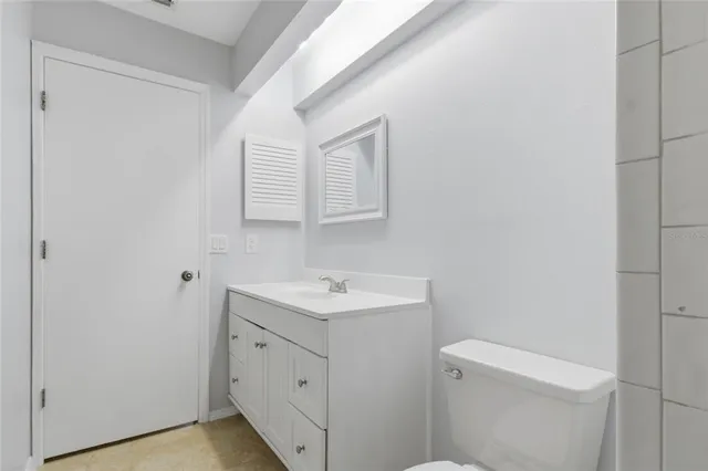 a bathroom with a toilet sink vanity and mirror