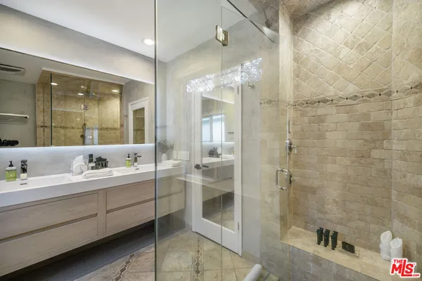 a bathroom with a double vanity sink mirror and shower
