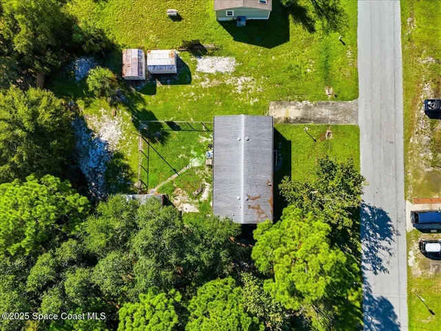 an aerial view of a residential houses with outdoor space and trees all around