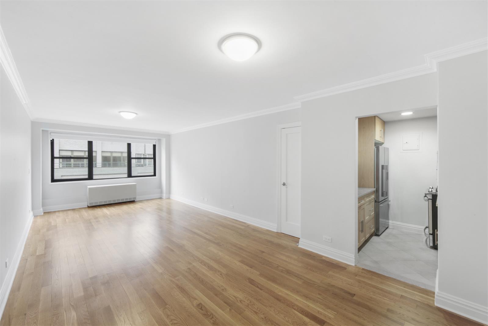 141 East 33rd Street, Unit 15H Manhattan, NY 10016 - Photo 3 of 9 a view of an empty room with window and wooden floor