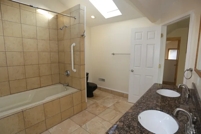 a bathroom with a granite countertop sink a toilet and shower