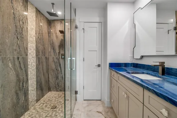 a bathroom with a granite countertop sink a mirror and shower