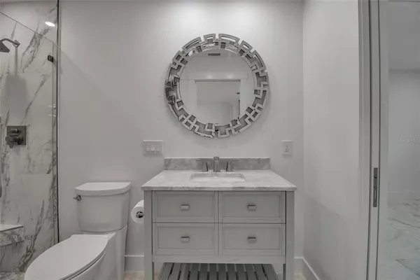 a bathroom with a granite countertop sink toilet a mirror and shower