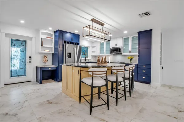a kitchen with stainless steel appliances kitchen island granite countertop a refrigerator and cabinets