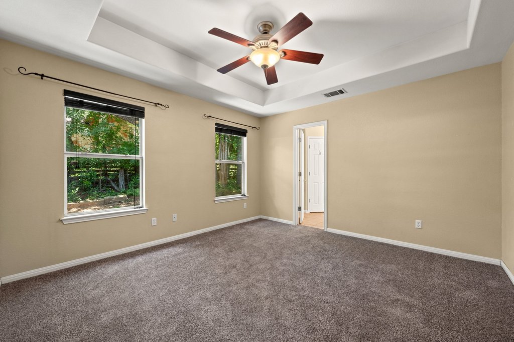 5208 Sioux Lane Austin, TX 78734 - Photo 20 of 35 A spacious bedroom features a tray ceiling, ceiling fan, and ample natural light from two large windows.
