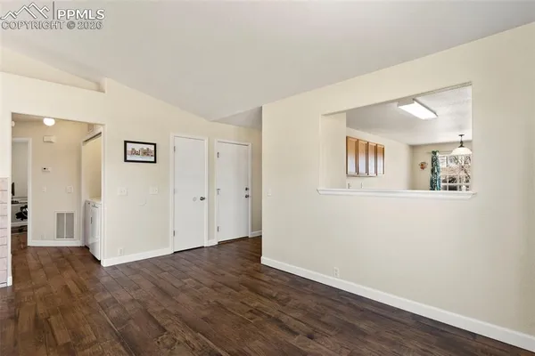 a view of a big room with wooden floor and windows