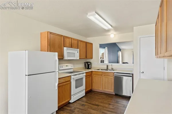 a kitchen with a sink a refrigerator a counter top space and cabinets