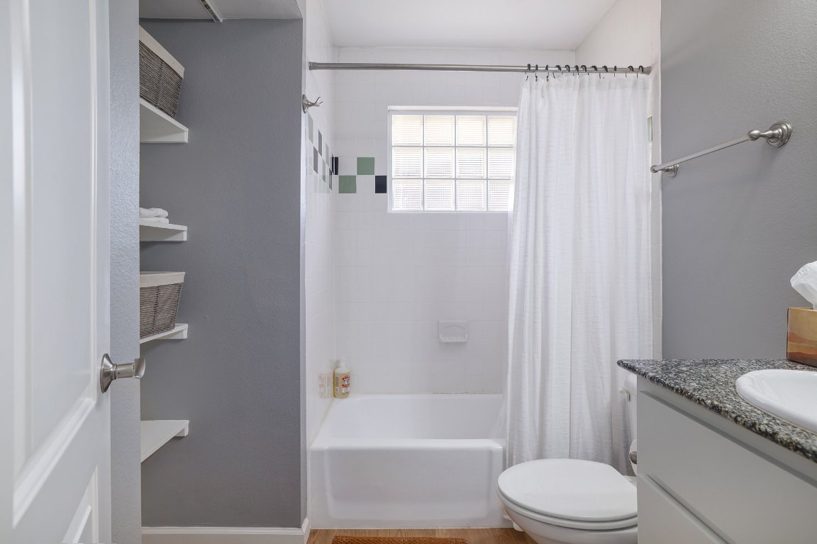 1422 Collier Street, Unit 105 Austin, TX 78704 - Photo 17 of 27 a bathroom with a granite countertop toilet a sink and a bathtub