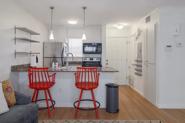 a kitchen with stainless steel appliances granite countertop a refrigerator a sink a stove a dining table and chairs