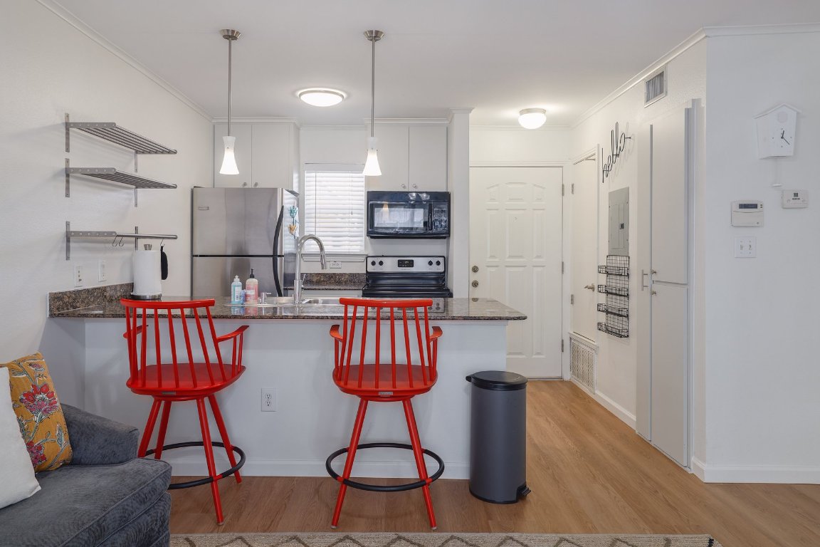 1422 Collier Street, Unit 105 Austin, TX 78704 - Photo 6 of 27 a kitchen with stainless steel appliances granite countertop a refrigerator a sink a stove a dining table and chairs