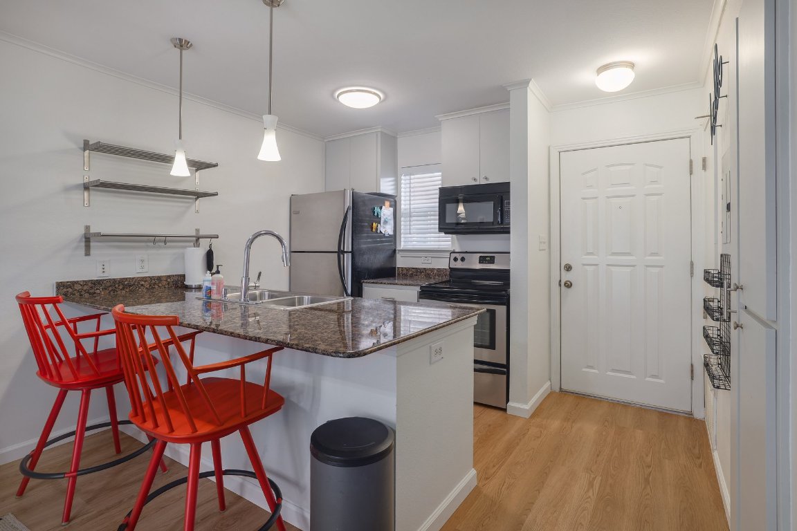 1422 Collier Street, Unit 105 Austin, TX 78704 - Photo 7 of 27 a kitchen with stainless steel appliances granite countertop a sink and a refrigerator