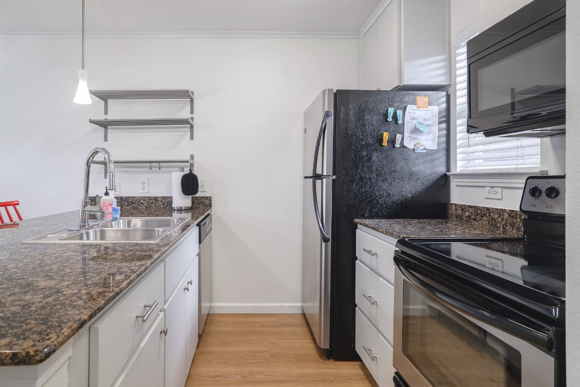 1422 Collier Street, Unit 105 Austin, TX 78704 - Photo 9 of 27 a kitchen with stainless steel appliances granite countertop a sink stove and refrigerator