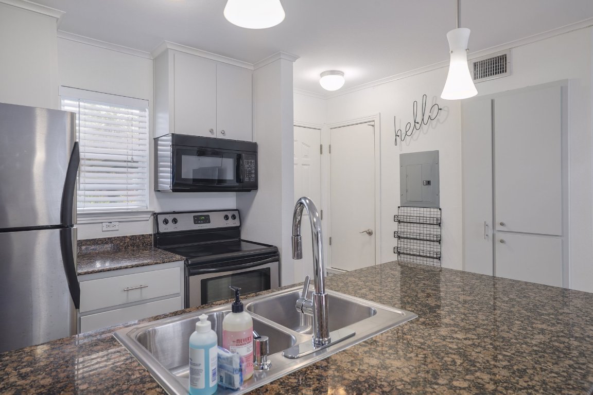 1422 Collier Street, Unit 105 Austin, TX 78704 - Photo 10 of 27 a kitchen with granite countertop a refrigerator and a sink
