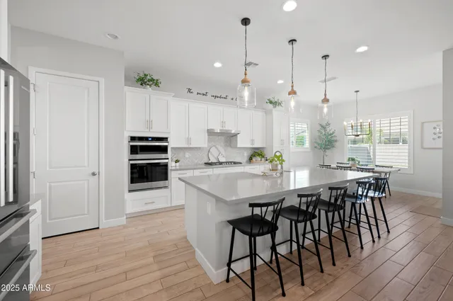 a kitchen with kitchen island a dining table chairs stainless steel appliances and cabinets