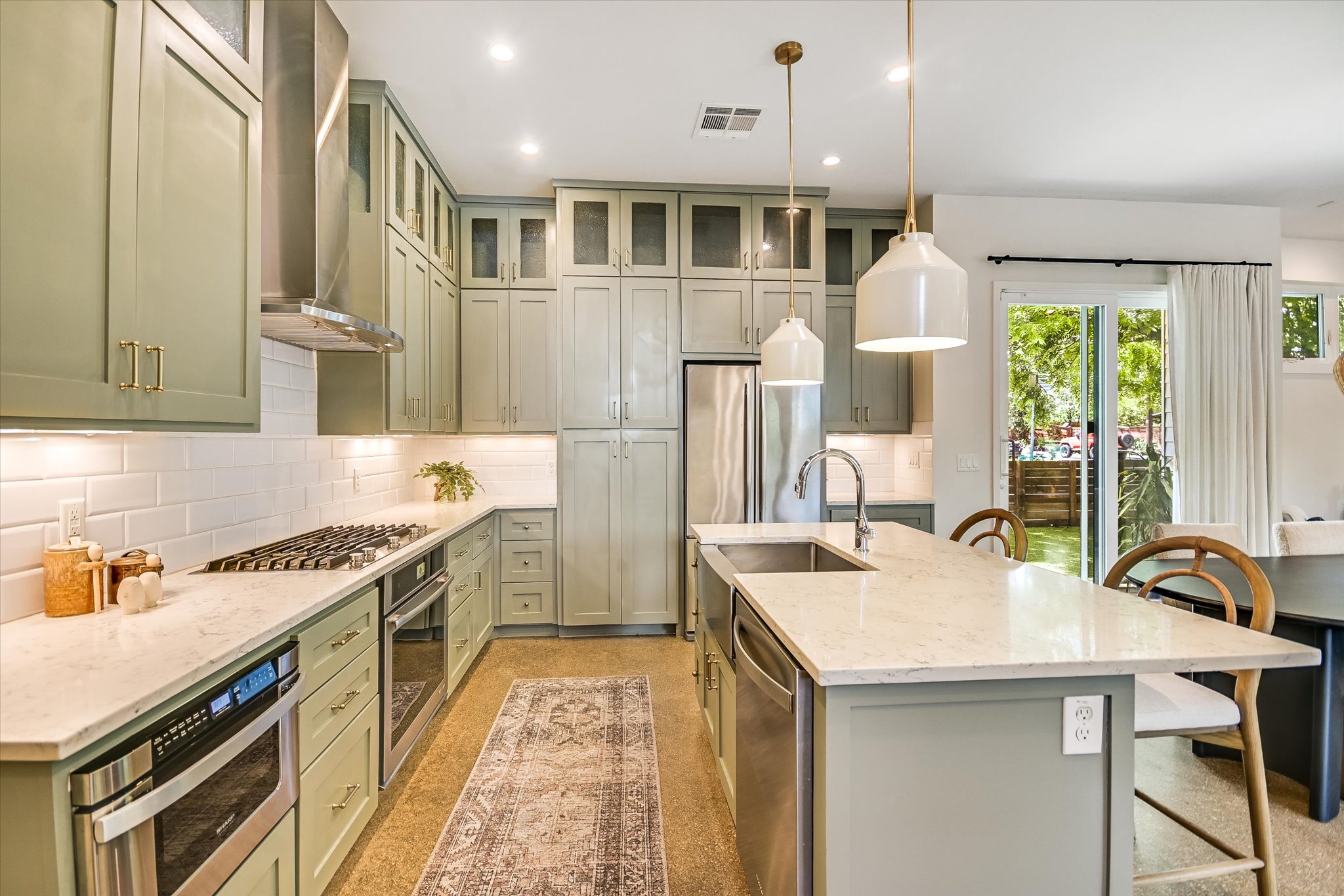 1605 Hether Street Austin, TX 78704 - Photo 12 of 26 Kitchen featuring abundant pale green cabinetry, stainless steel appliances, white subway tile backsplash, and light-colored countertops