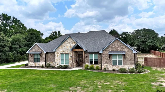 a front view of a house with a garden and trees