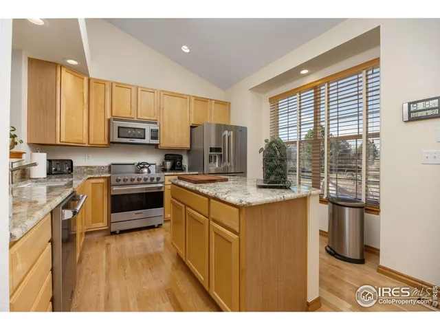 a kitchen with kitchen island granite countertop a stove a sink a refrigerator and a microwave