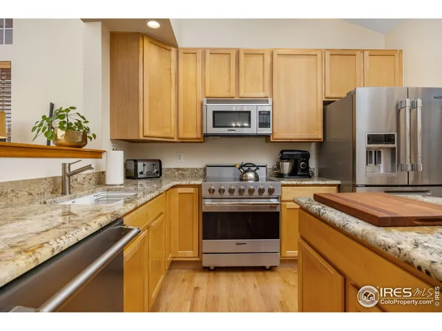 a kitchen with stainless steel appliances granite countertop a sink a stove and a refrigerator