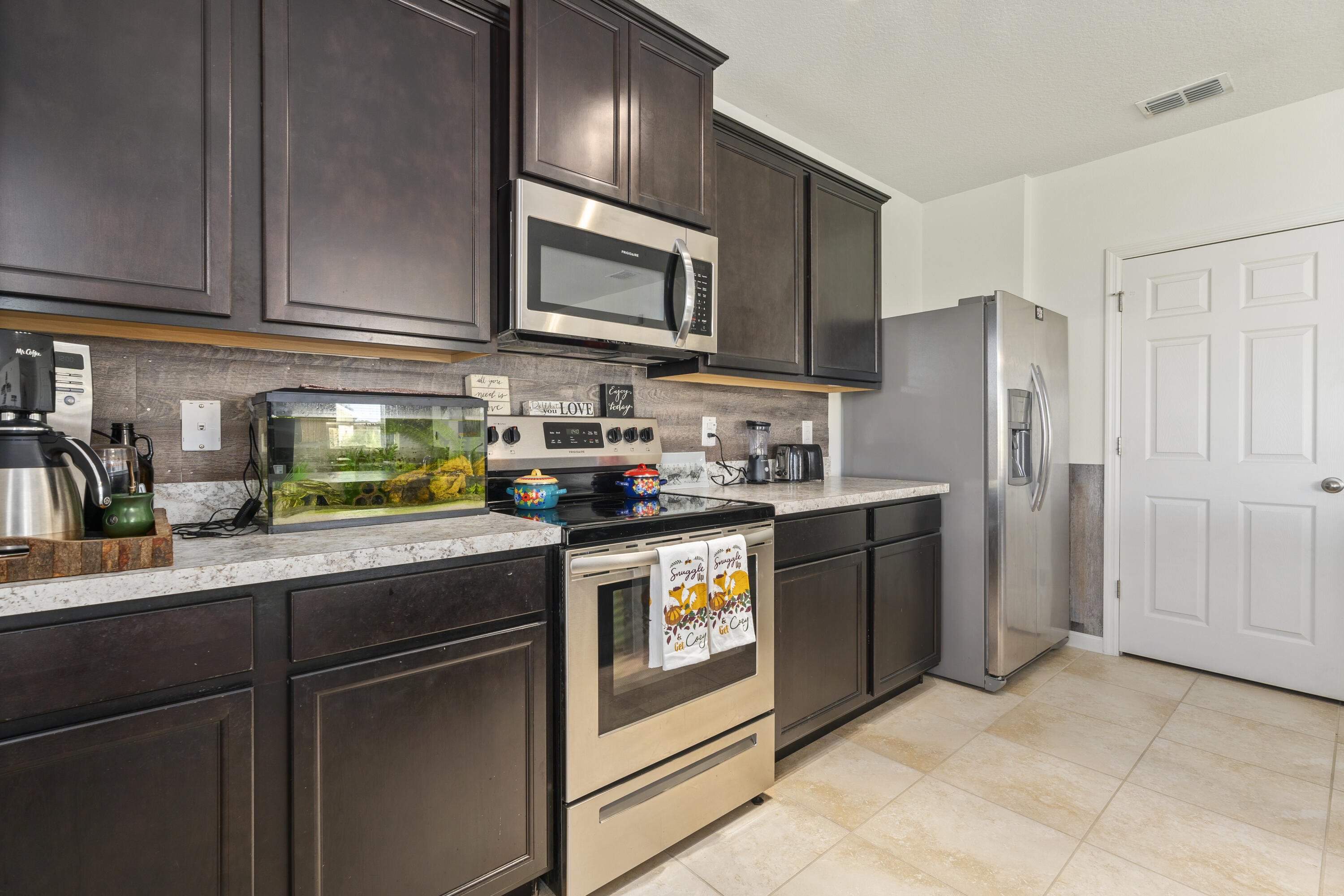 3100 Yellowstone Circle Fort Pierce, FL 34945 - Photo 14 of 28 a kitchen with stainless steel appliances granite countertop a refrigerator a stove a sink and dishwasher with wooden cabinets