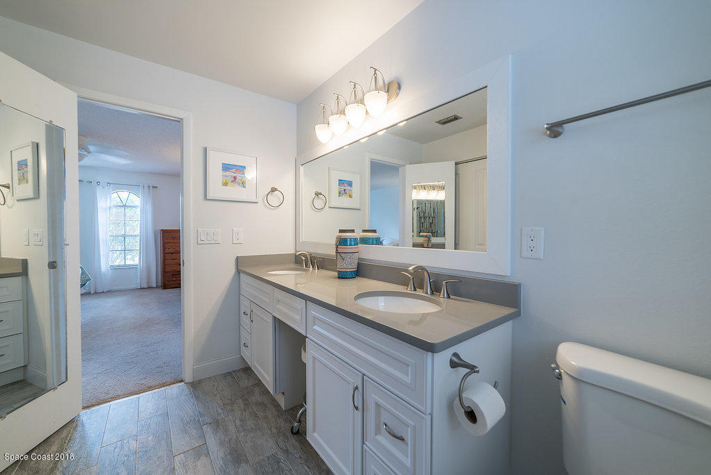 700 Montclair Road Northeast Palm Bay, FL 32905 - Photo 39 of 46 a bathroom with a granite countertop sink a toilet and a mirror