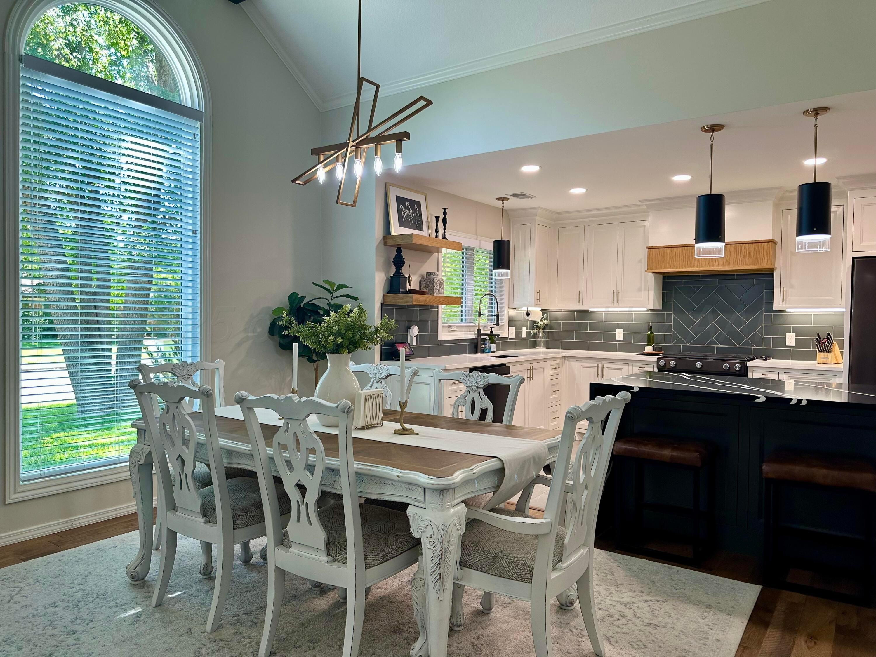 7714 Baughman Drive Amarillo, TX 79121 - Photo 9 of 37 a kitchen with stainless steel appliances kitchen island granite countertop a dining table chairs and white cabinets