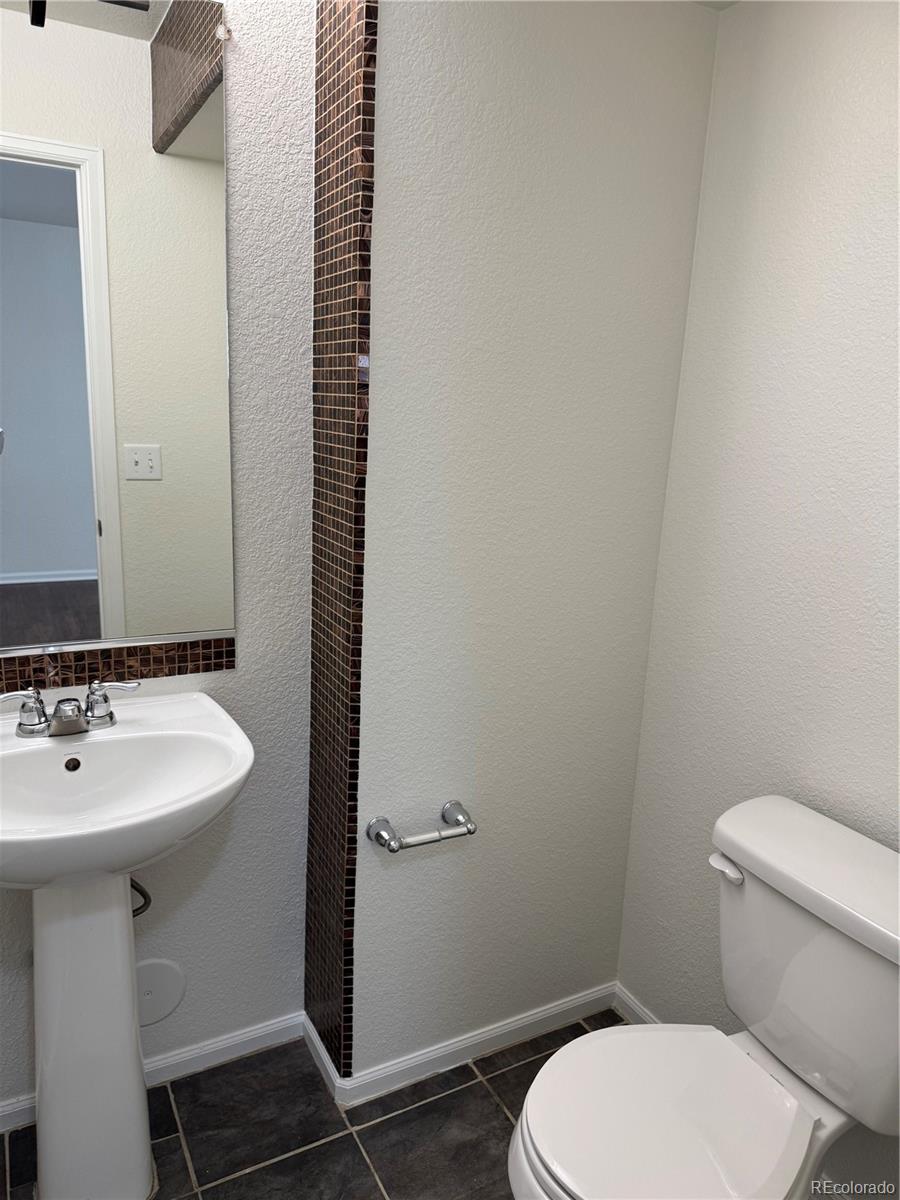 4726 Andes Street Denver, CO 80249 - Photo 4 of 17 a bathroom with a toilet a sink and mirror