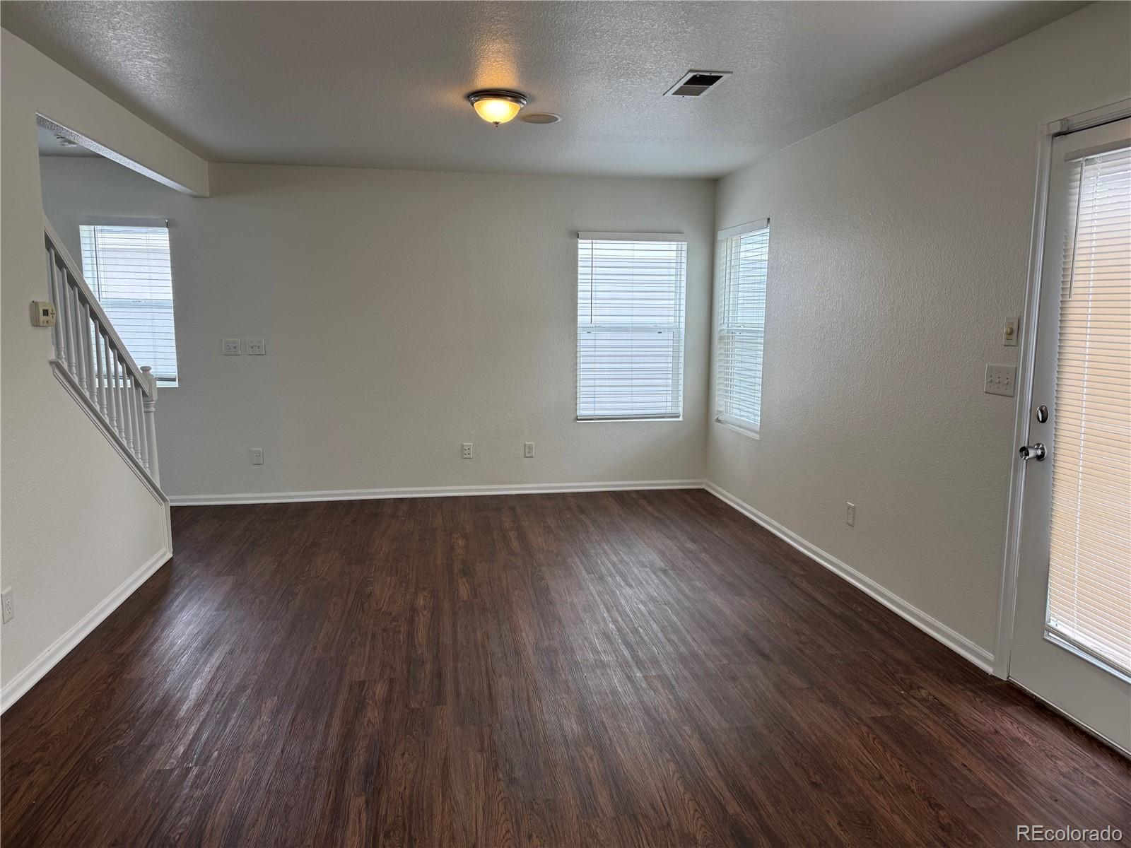 4726 Andes Street Denver, CO 80249 - Photo 5 of 17 an empty room with wooden floor and windows