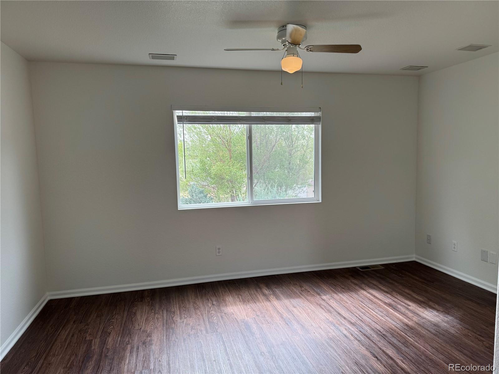 4726 Andes Street Denver, CO 80249 - Photo 8 of 17 an empty room with wooden floor chandelier fan and windows