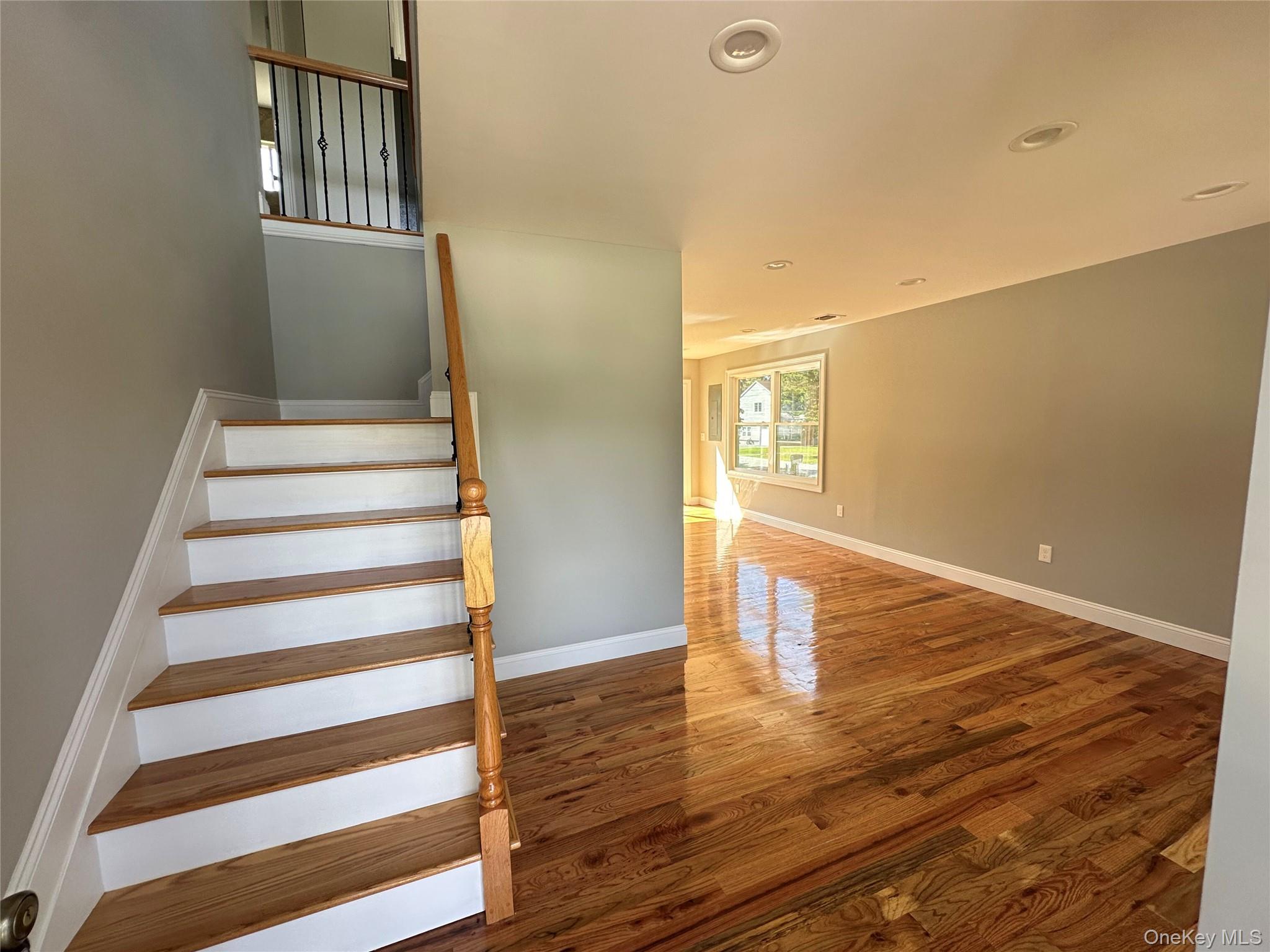 214 Forest Road West Mastic Beach, NY 11951 - Photo 9 of 24 Hardwood flooring spans the open-concept living area, featuring recessed lighting and white baseboards