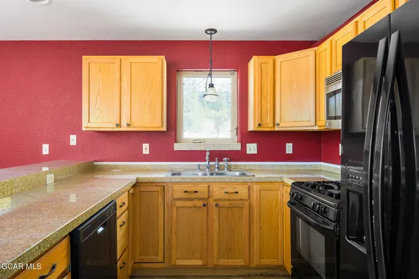a kitchen with a sink a stove cabinets and a window