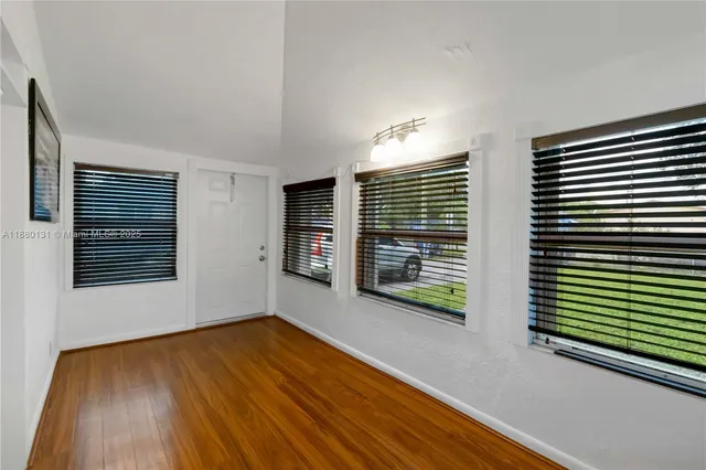a view of an empty room with glass door and wooden floor