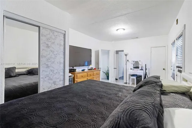 a bedroom with a bed and a flat tv screen on a dresser