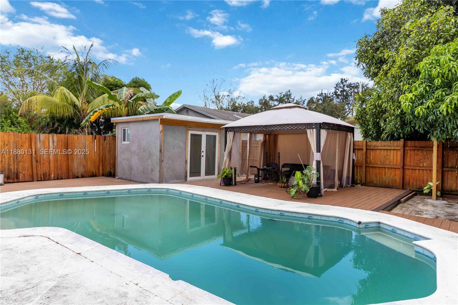 5740 Lincoln Street Hollywood, FL 33021 - Photo 2 of 28 a backyard of a house with table and chairs under an umbrella