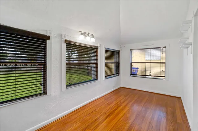 a view of an empty room with glass door and wooden floor
