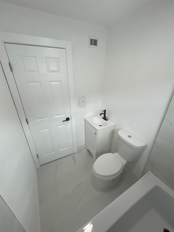 1457 West 31st Street, Unit 1 Riviera Beach, FL 33404 - Photo 14 of 16 a white toilet sitting next to a bathroom sink