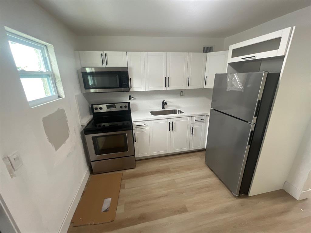 1457 West 31st Street, Unit 1 Riviera Beach, FL 33404 - Photo 6 of 16 a kitchen with a refrigerator stove and sink