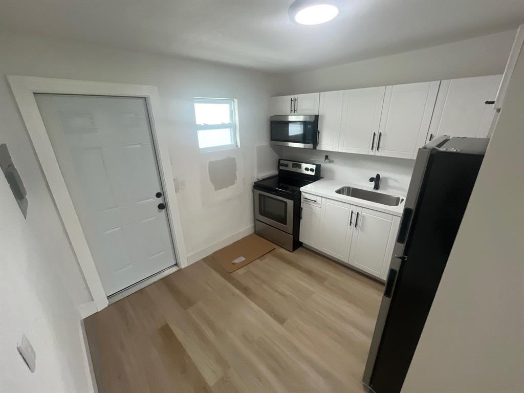 1457 West 31st Street, Unit 1 Riviera Beach, FL 33404 - Photo 7 of 16 a kitchen with stainless steel appliances a refrigerator stove microwave and sink