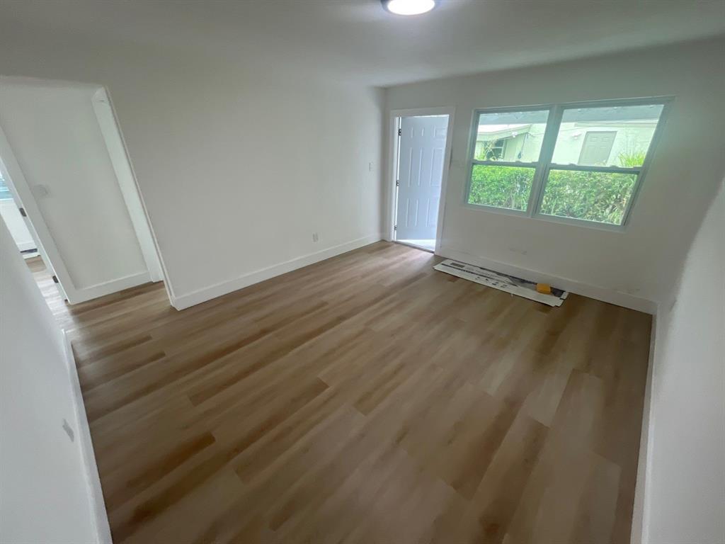 1457 West 31st Street, Unit 1 Riviera Beach, FL 33404 - Photo 8 of 16 an empty room with wooden floor and windows