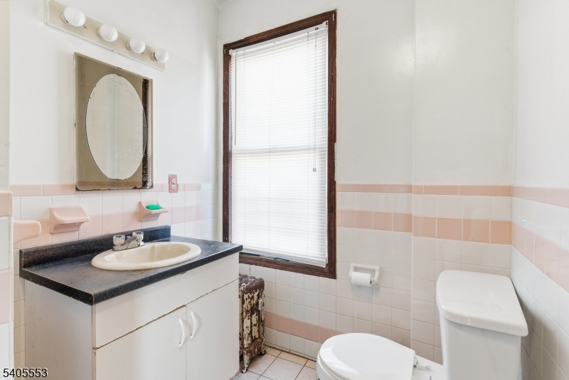 197 16th Avenue Paterson, NJ 07501 - Photo 13 of 23 a bathroom with a sink a toilet and a mirror
