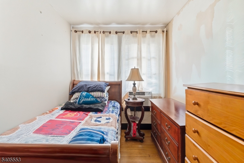 197 16th Avenue Paterson, NJ 07501 - Photo 7 of 23 a bedroom with a bed and a dresser next to a window