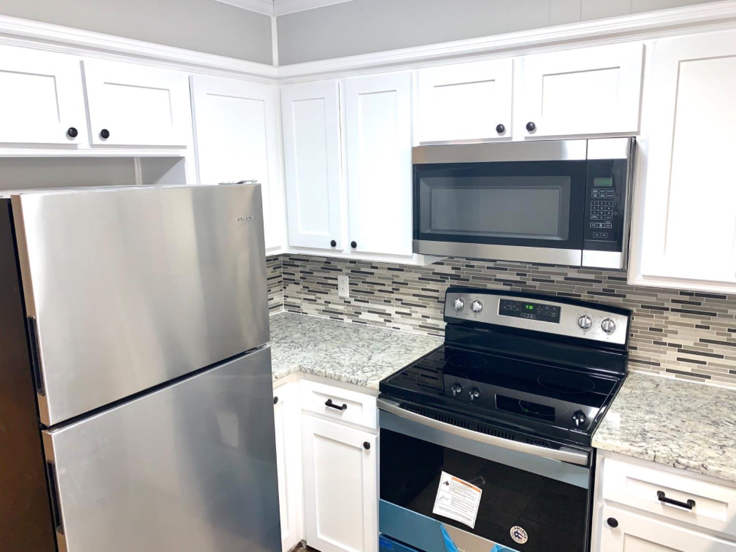 5708 91st Street Lubbock, TX 79424 - Photo 8 of 26 a kitchen with granite countertop a refrigerator stove and microwave